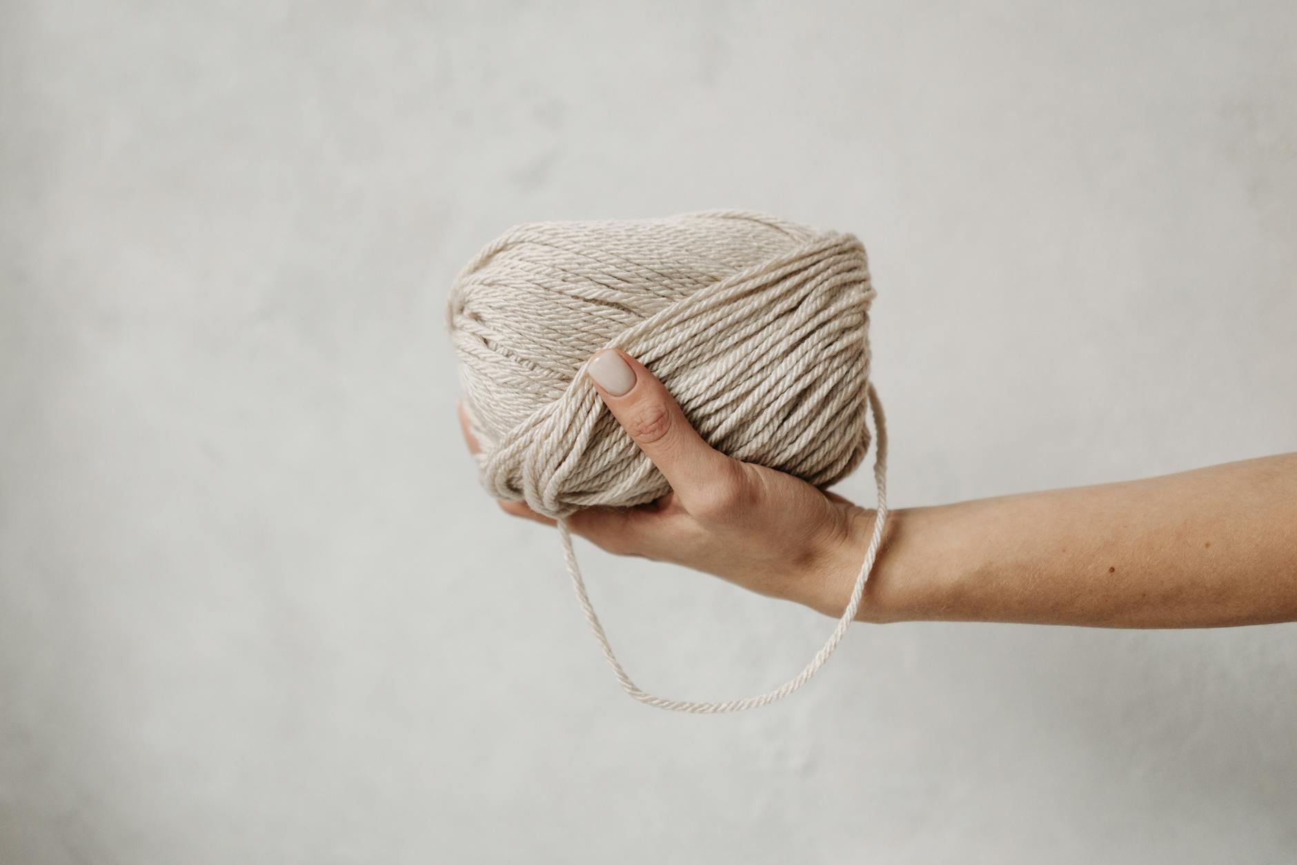 person holding brown yarn roll